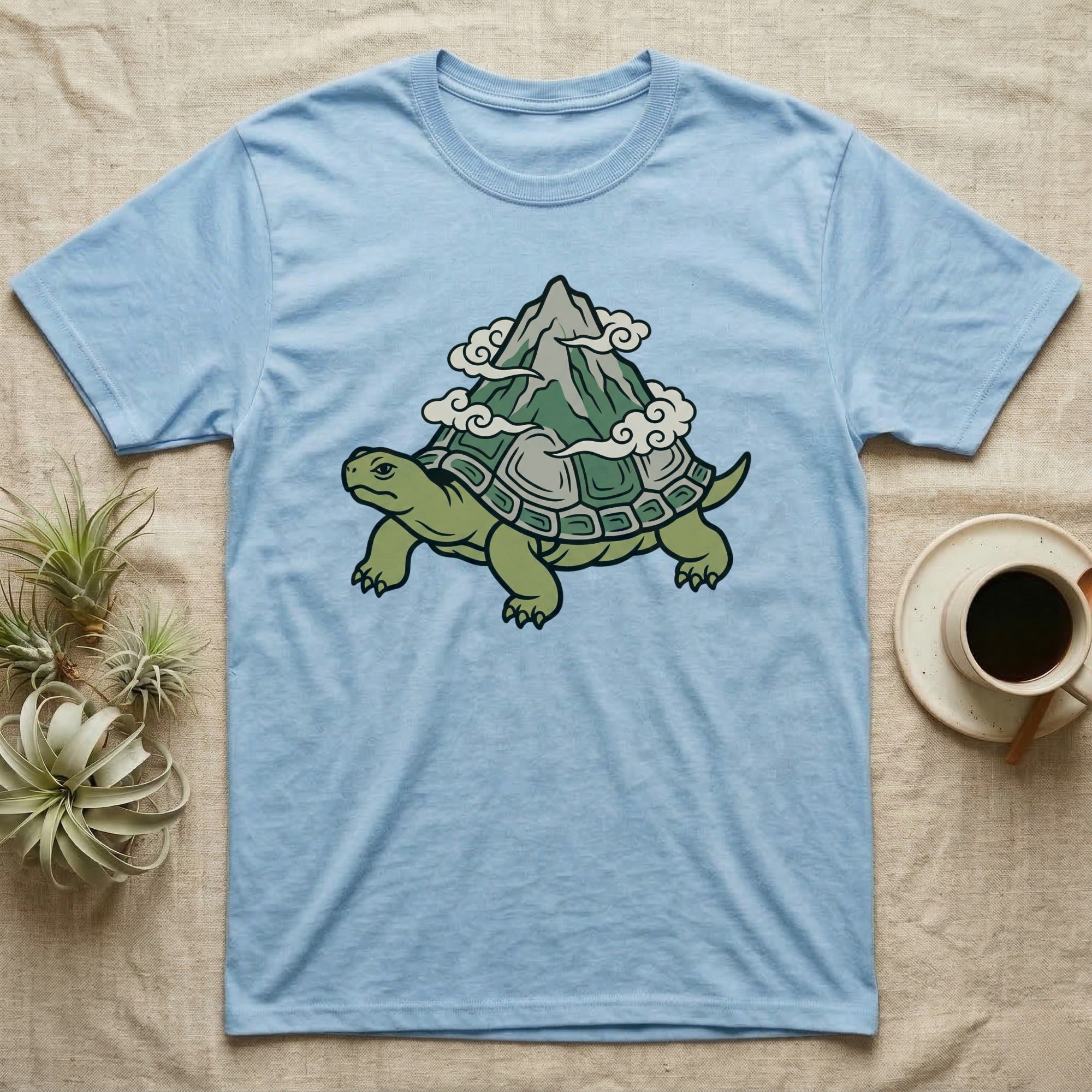Light blue t-shirt featuring a cartoon turtle with a mountain on its shell.