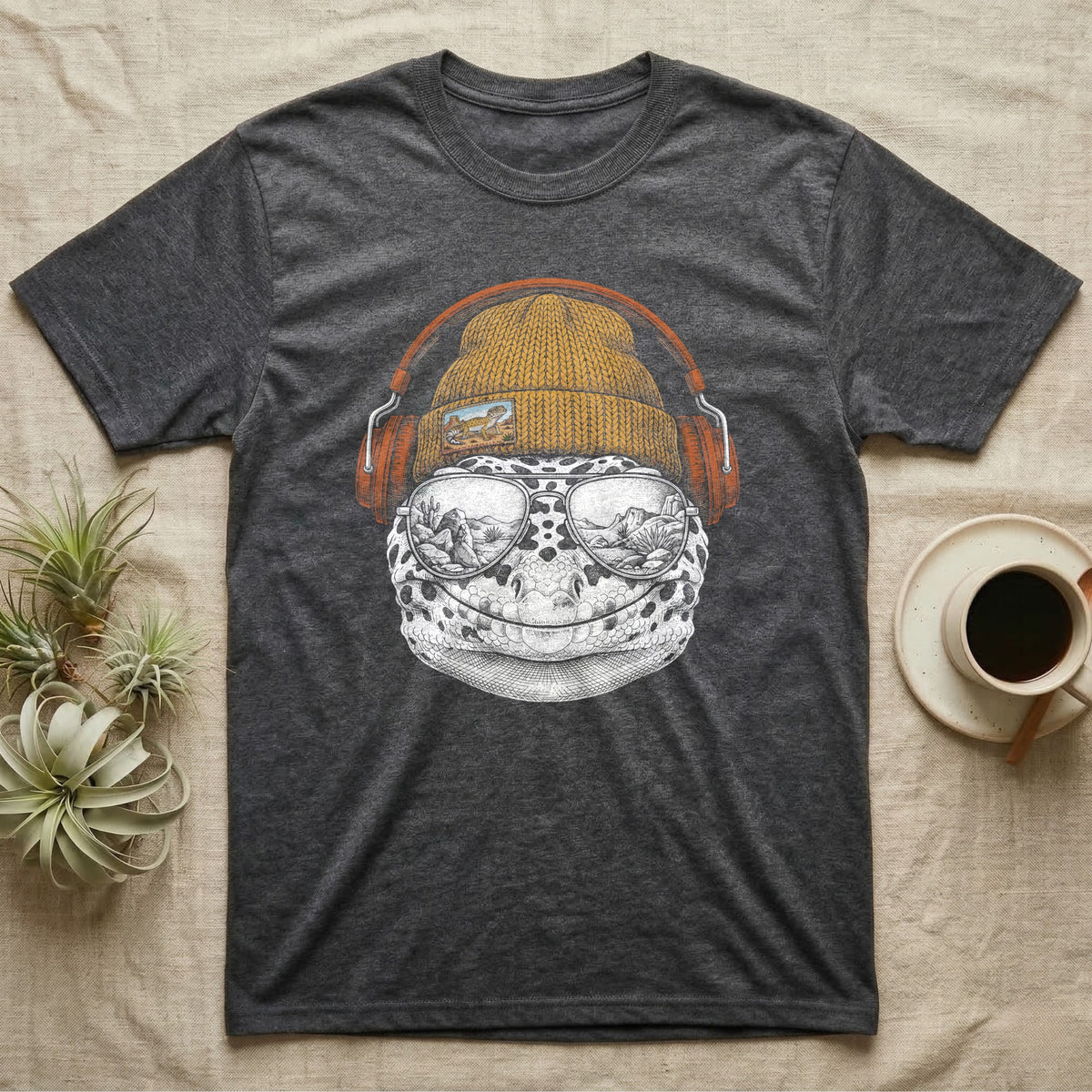 Leopard Gecko Headphones T-Shirt in Dark Heather — Engraved leopard gecko with spotted skin in a beanie and headphones, aviators reflecting a desert canyon.