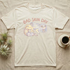 Cream t-shirt with "Bad Skin Day" text and gecko graphic.