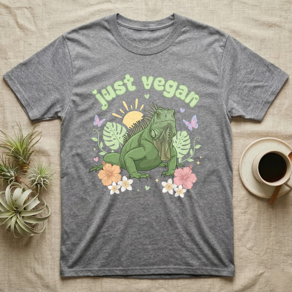 Green Iguana Baby T-Shirt in Sport Grey — Green iguana with spiky crest and dewlap among pastel leaves and flowers under puffy green bubble text "just vegan".