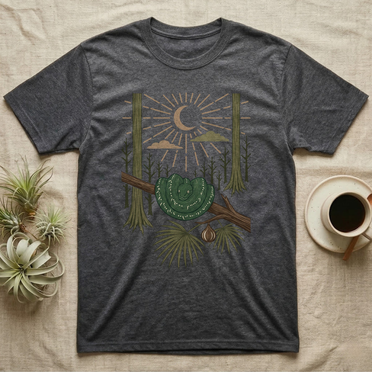 Green Tree Python Home Range T-Shirt in Dark Heather — Woodcut-style illustration of a green tree python coiled in a saddle over a branch with palms and tall trunks behind, no on-shirt text.
