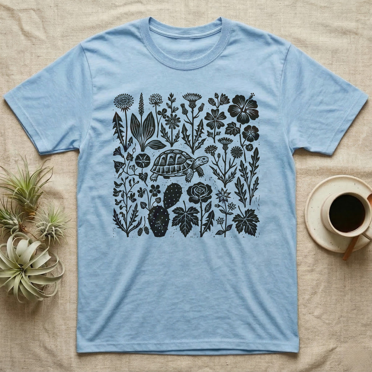 Hermann's Tortoise Forage T-Shirt in Light Blue — One-ink linocut of twenty forage plants with a small Hermann's tortoise walking among them