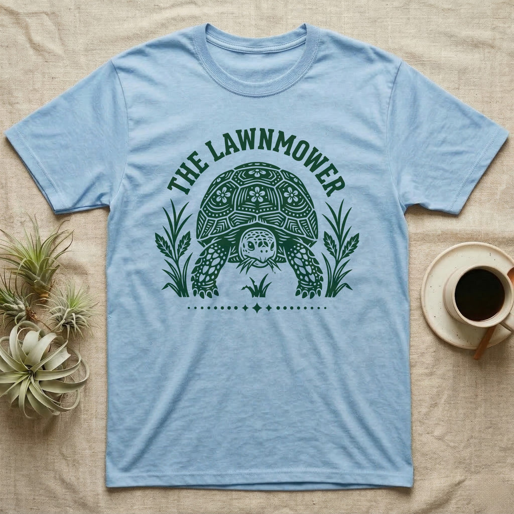 Sulcata Tortoise Under Lawn T-Shirt in Light Blue — Engraved sulcata tortoise in white line, head down and legs braced mid-dig, under retro script reading UNDER THE LAWN.