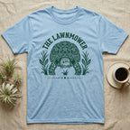 Sulcata Tortoise Under Lawn T-Shirt in Light Blue — Engraved sulcata tortoise in white line, head down and legs braced mid-dig, under retro script reading UNDER THE LAWN.