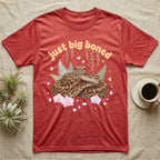 Burmese Python Baby T-Shirt in Heather Red — Massive coiled Burmese python among pastel ferns and orchids under puffy butterscotch bubble text "just big boned".