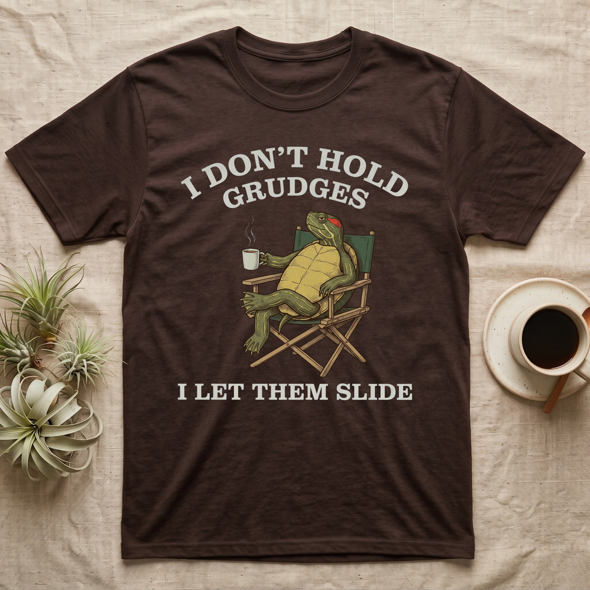 Red-Eared Slider Grudges T-Shirt in Dark Chocolate — Engraved red-eared slider lounging in a camp chair with tea under I Don't Hold Grudges I Let Them Slide