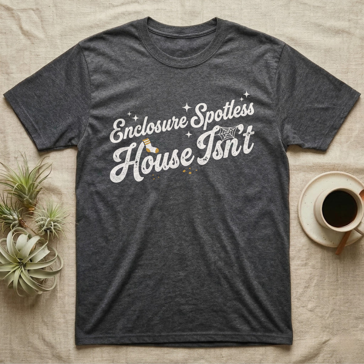 Terrarium Spotless House T-Shirt in Dark Heather — Retro script reading Enclosure Spotless with sparkles above grubby lettering reading House Isn't with a sock, cobweb and crumbs