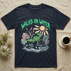 Green Basilisk Feral T-Shirt in Navy — Green plumed basilisk sprinting across water below a dripping aqua-green metal "Walks On Water" wordmark