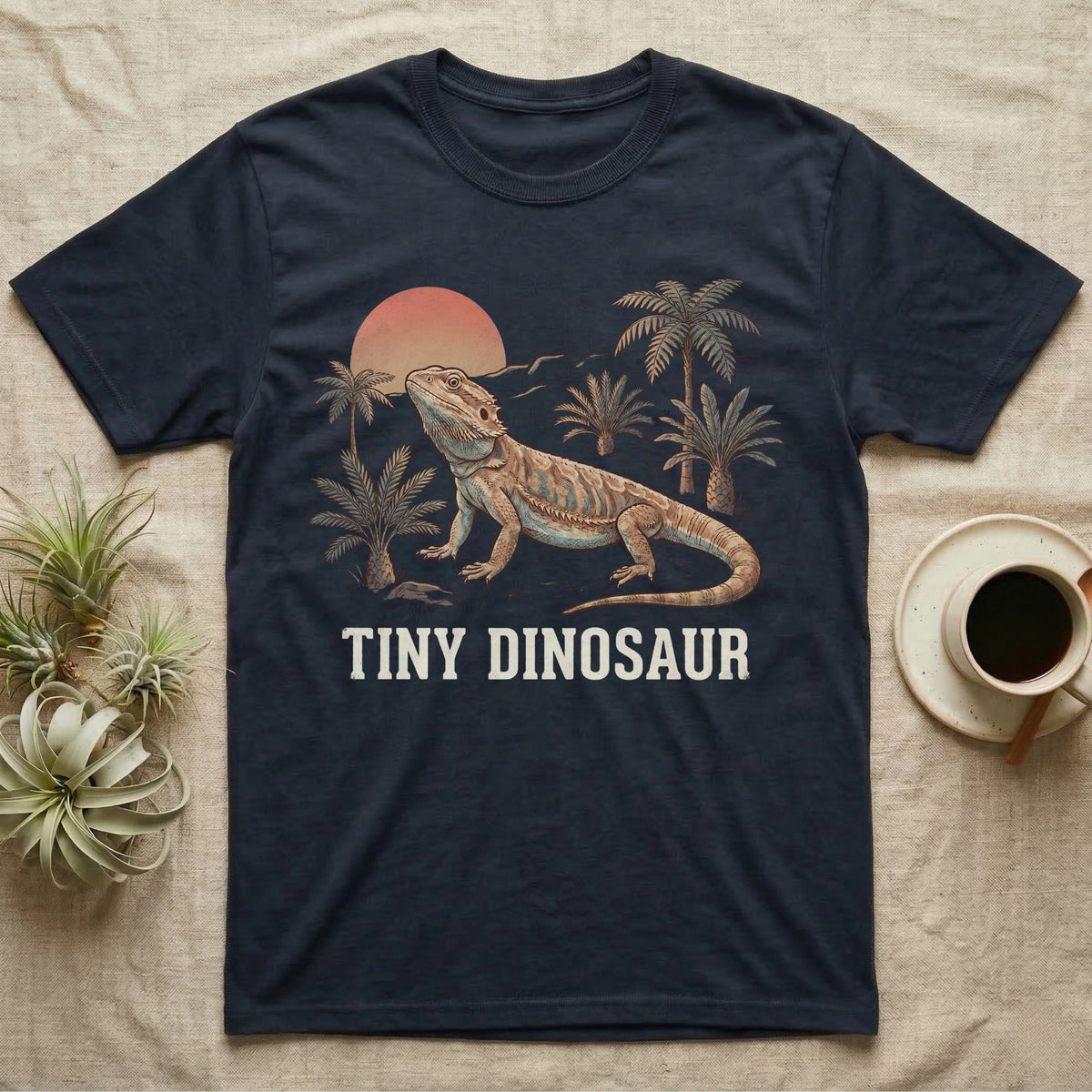 Tiny Dinosaur Bearded Dragon T-Shirt in Navy — Retro natural-history illustration of a bearded dragon in profile in a prehistoric landscape with a distressed "Tiny Dinosaur" caption.