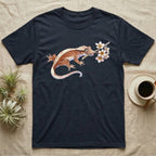 Crested Gecko Blossom T-Shirt in Navy — Watercolor illustration of a rust-brown crested gecko holding a frangipani blossom sprig, on a dark grey t-shirt.