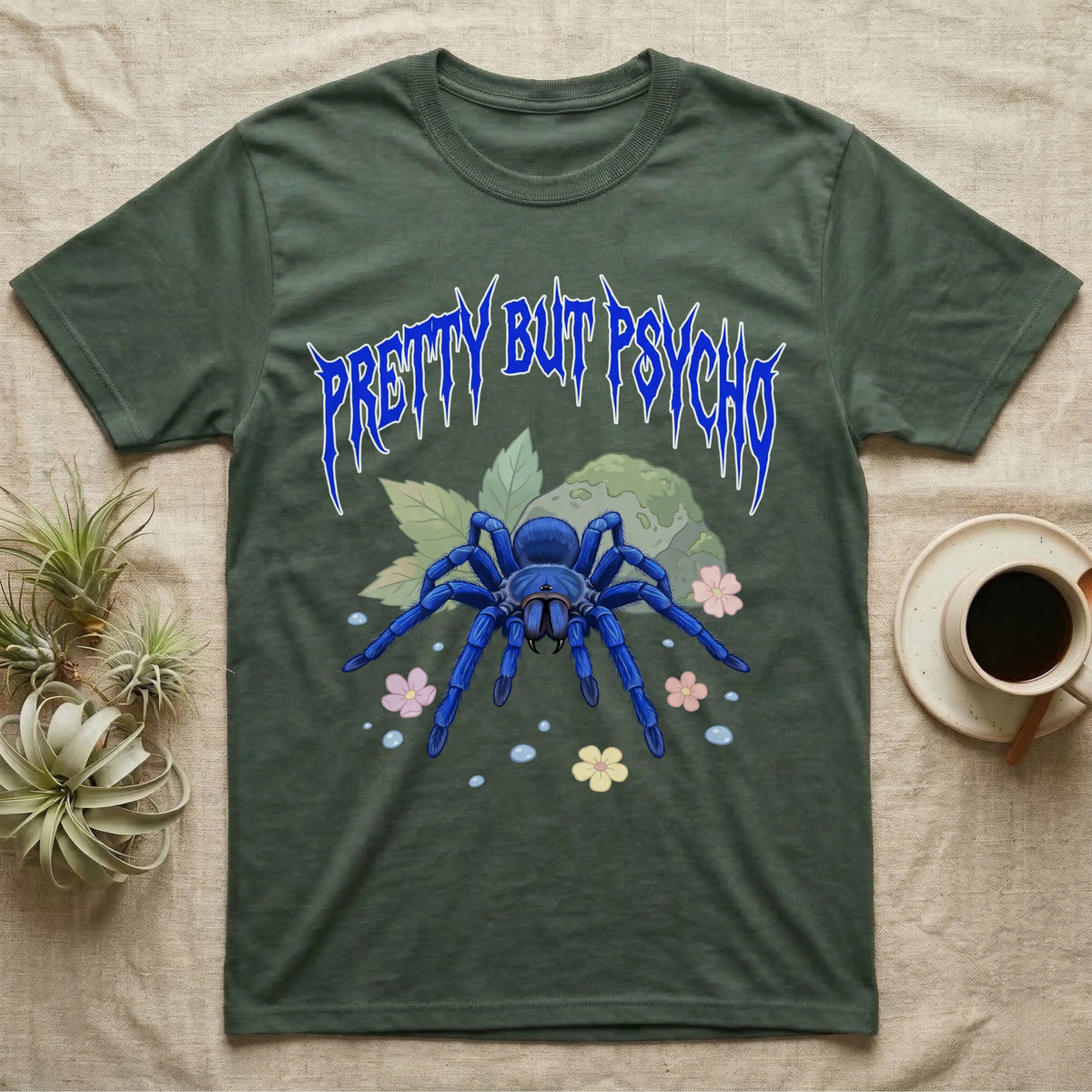 Cobalt Blue Tarantula Feral T-Shirt in Military Green — Cobalt blue tarantula with electric-blue legs under jagged cobalt metal text PRETTY BUT PSYCHO with pastel blossoms