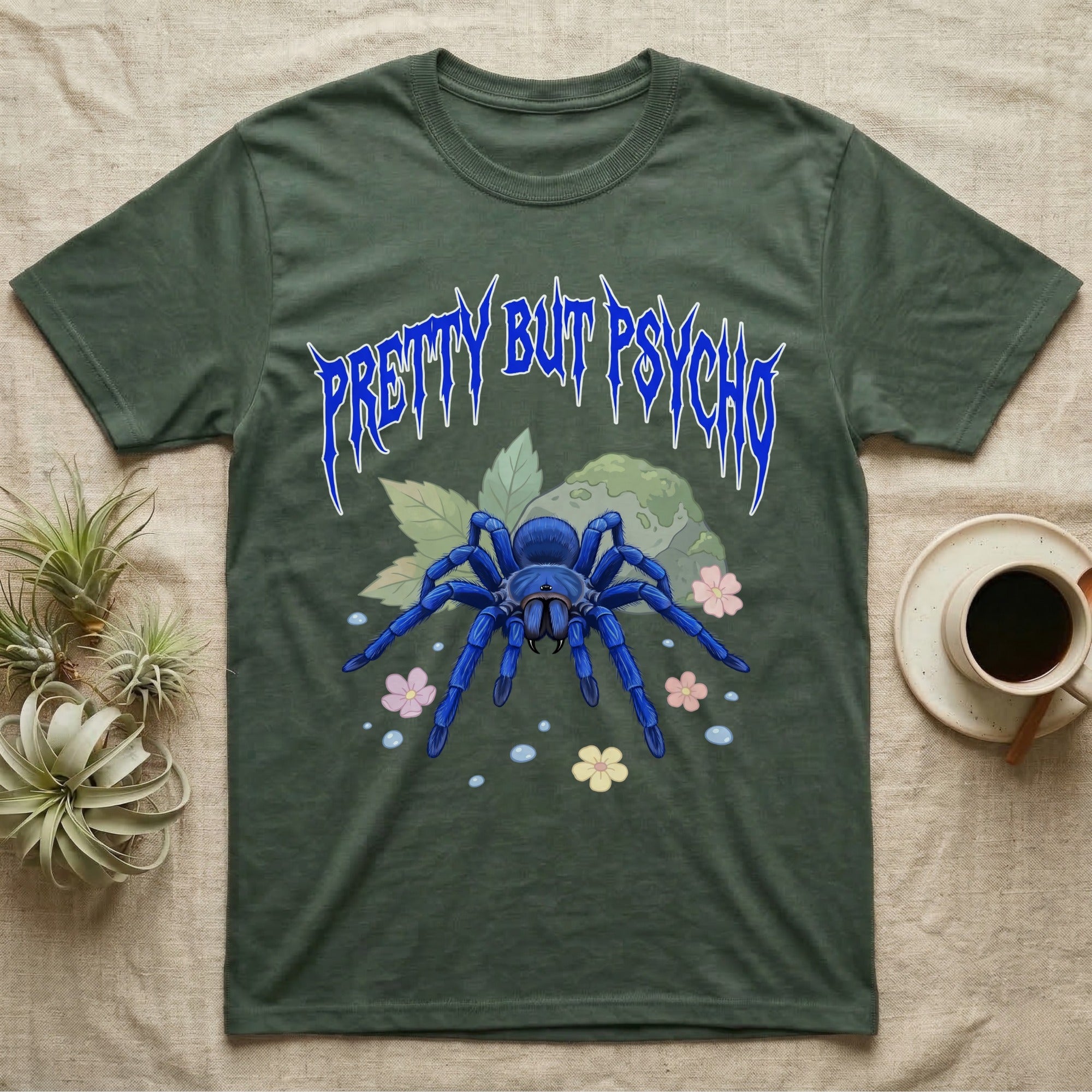 Cobalt Blue Tarantula Feral T-Shirt in Military Green — Cobalt blue tarantula with electric-blue legs under jagged cobalt metal text PRETTY BUT PSYCHO with pastel blossoms