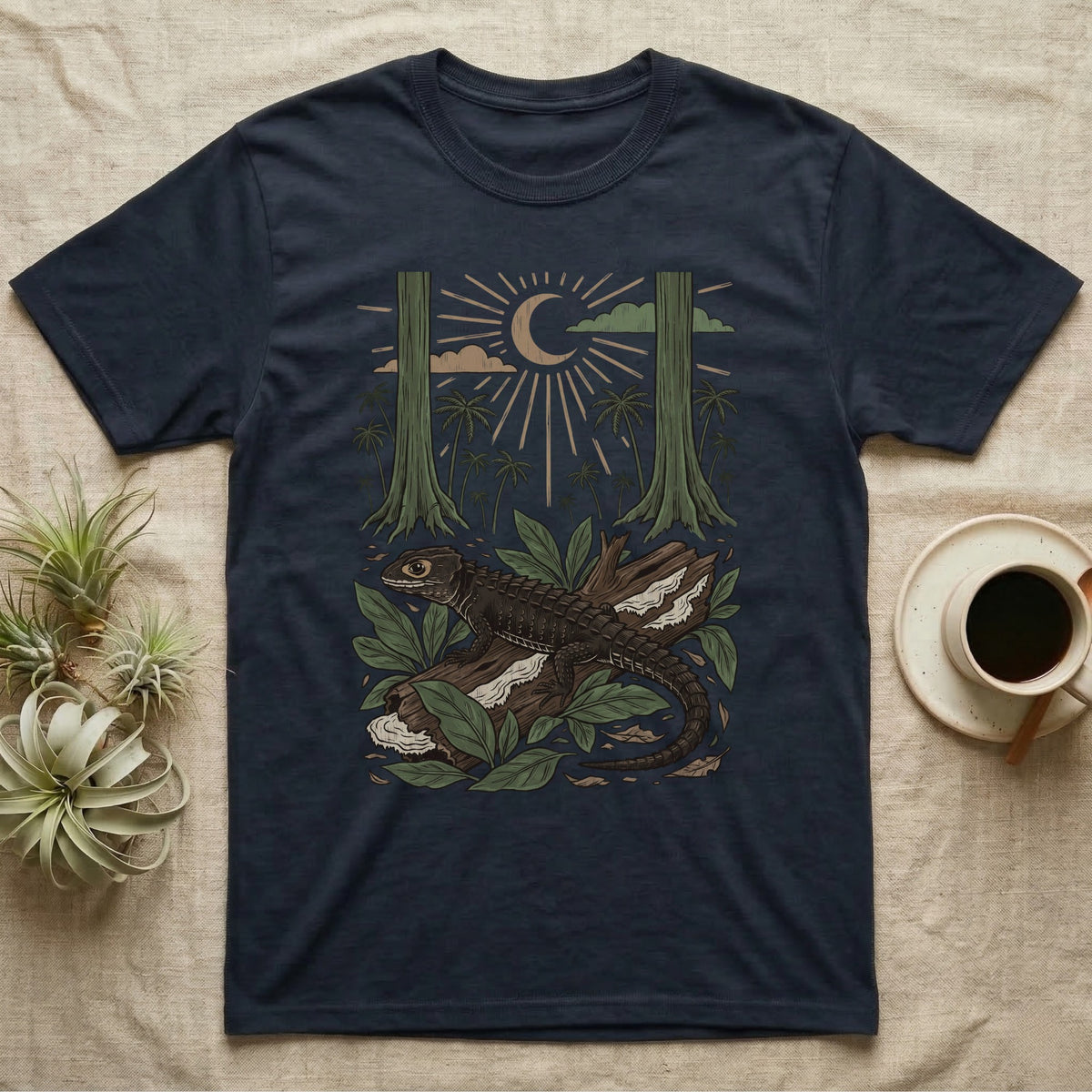 Crocodile Skink Home Range T-Shirt in Navy — Woodcut-style illustration of a red-eyed crocodile skink crouched on a rainforest log among broad leaves and palms, no on-shirt text.