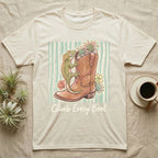 Cream t-shirt with a boot, gecko, plants, and "Climb Every Boot" text.
