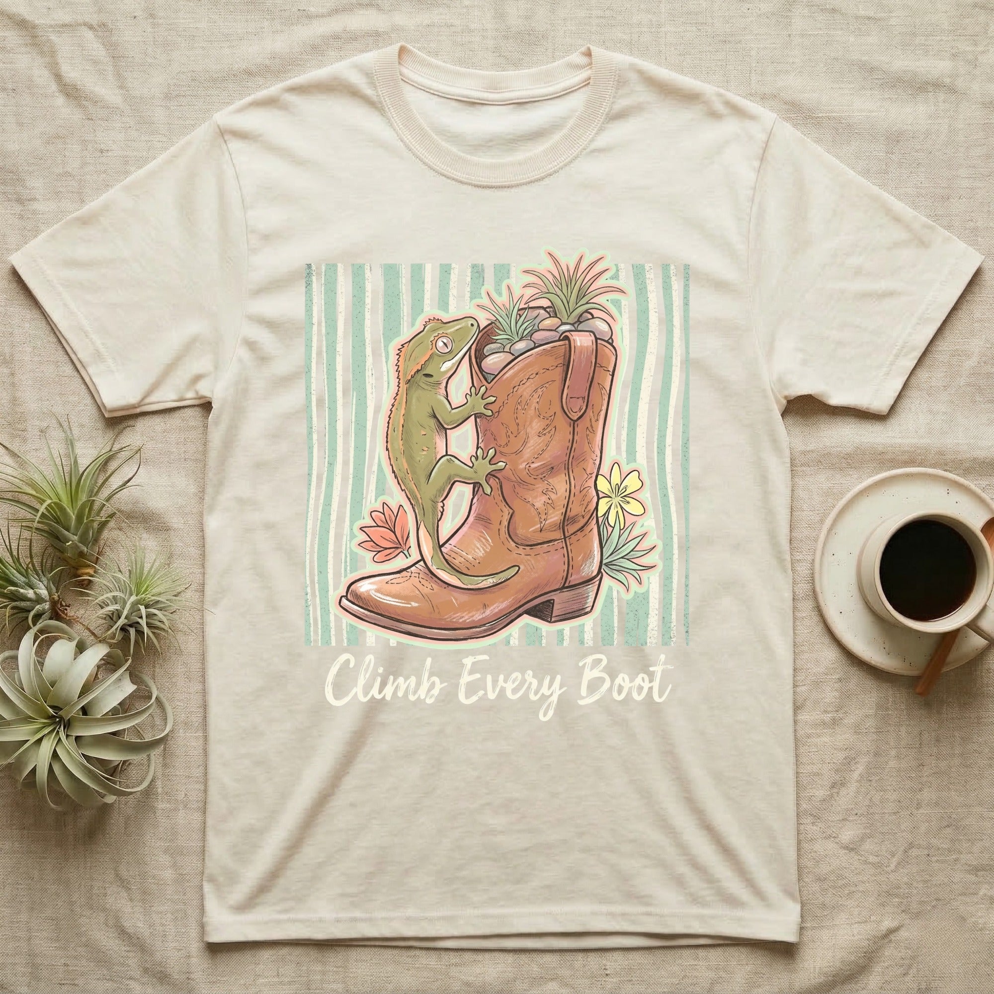 Cream t-shirt with a boot, gecko, plants, and "Climb Every Boot" text.