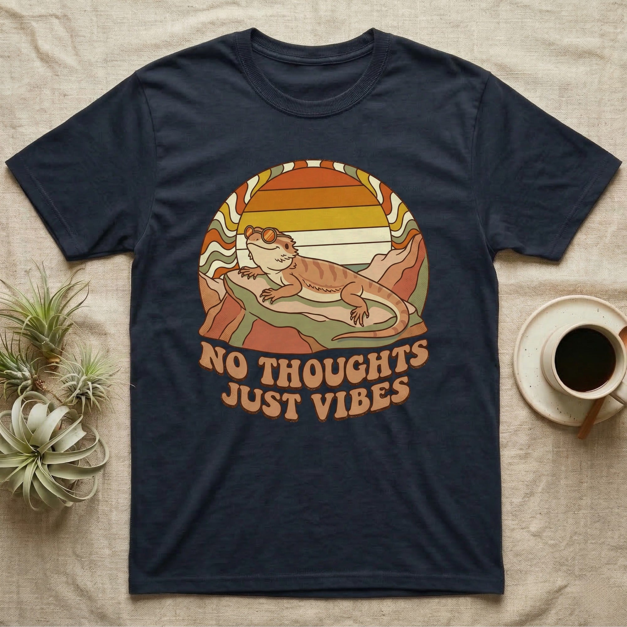 Navy t-shirt with retro sunset, mountains, lizard, and "NO THOUGHTS JUST VIBES" text.