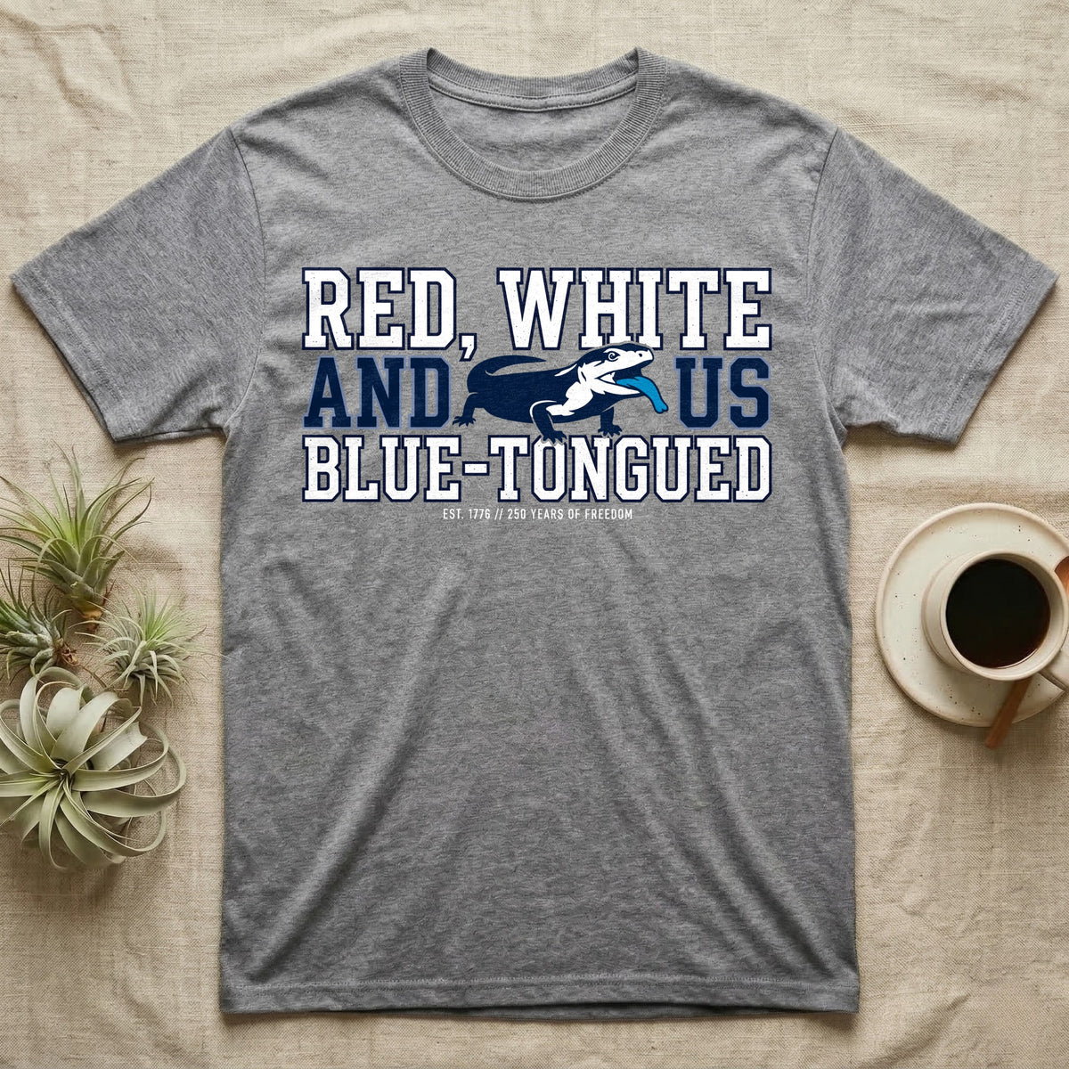 Blue-Tongued Skink 1776 T-Shirt in Sport Grey — Navy and white blue-tongued skink with tongue out between collegiate text reading Red, White and US Blue-Tongued.