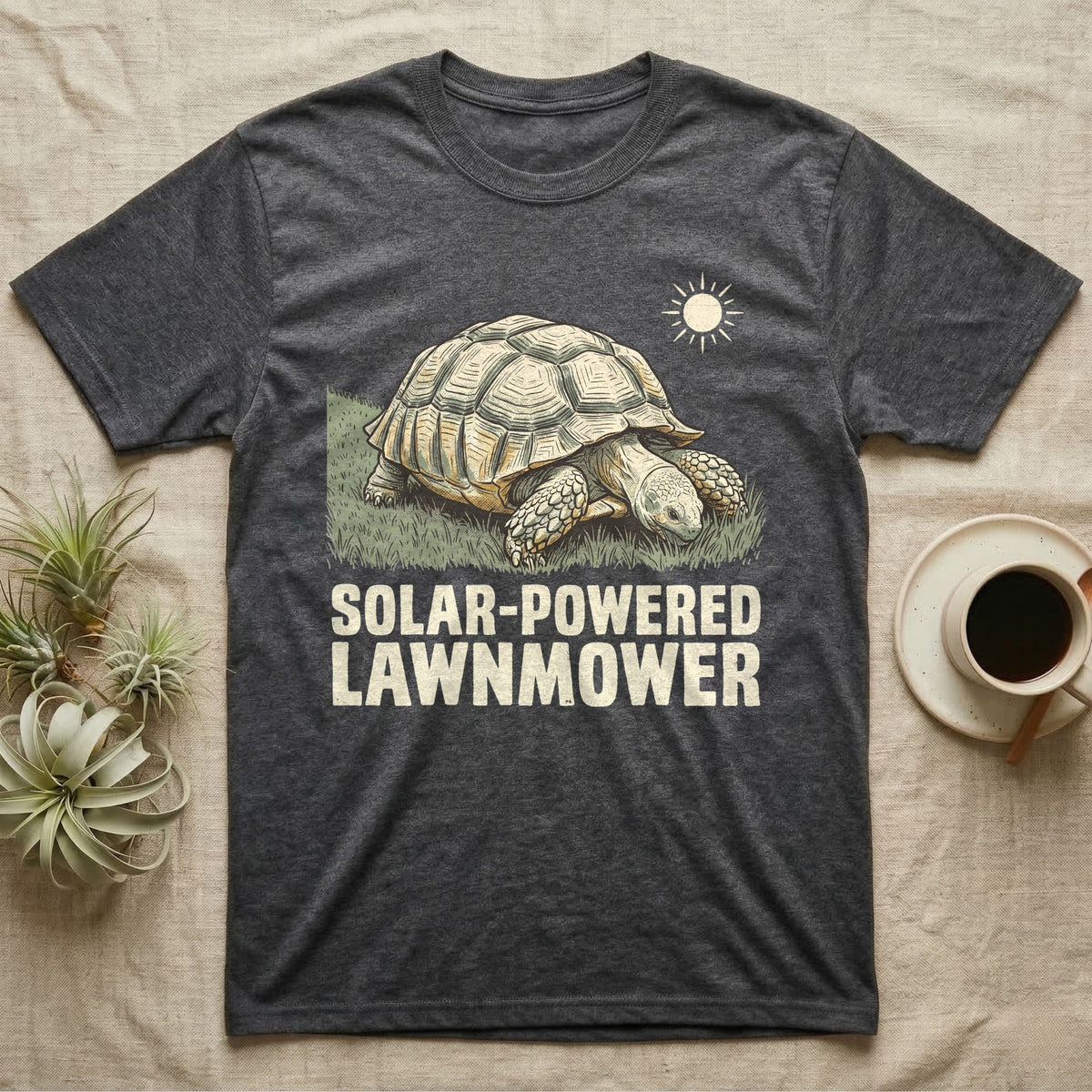 Solar Powered Lawnmower T-Shirt in Dark Heather — Retro-illustration of a sulcata tortoise grazing a lawn stripe under a sun motif with a Solar-Powered Lawnmower caption.