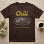 Snapping Turtle Chill T-Shirt in Dark Chocolate — White-line engraving of a snapping turtle floating among lily pads under the word Chill