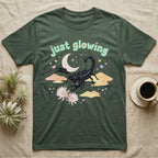 Emperor Scorpion Baby T-Shirt in Military Green — Black emperor scorpion, pincers raised, under a pastel moon and stars with puffy mint bubble text "just glowing".