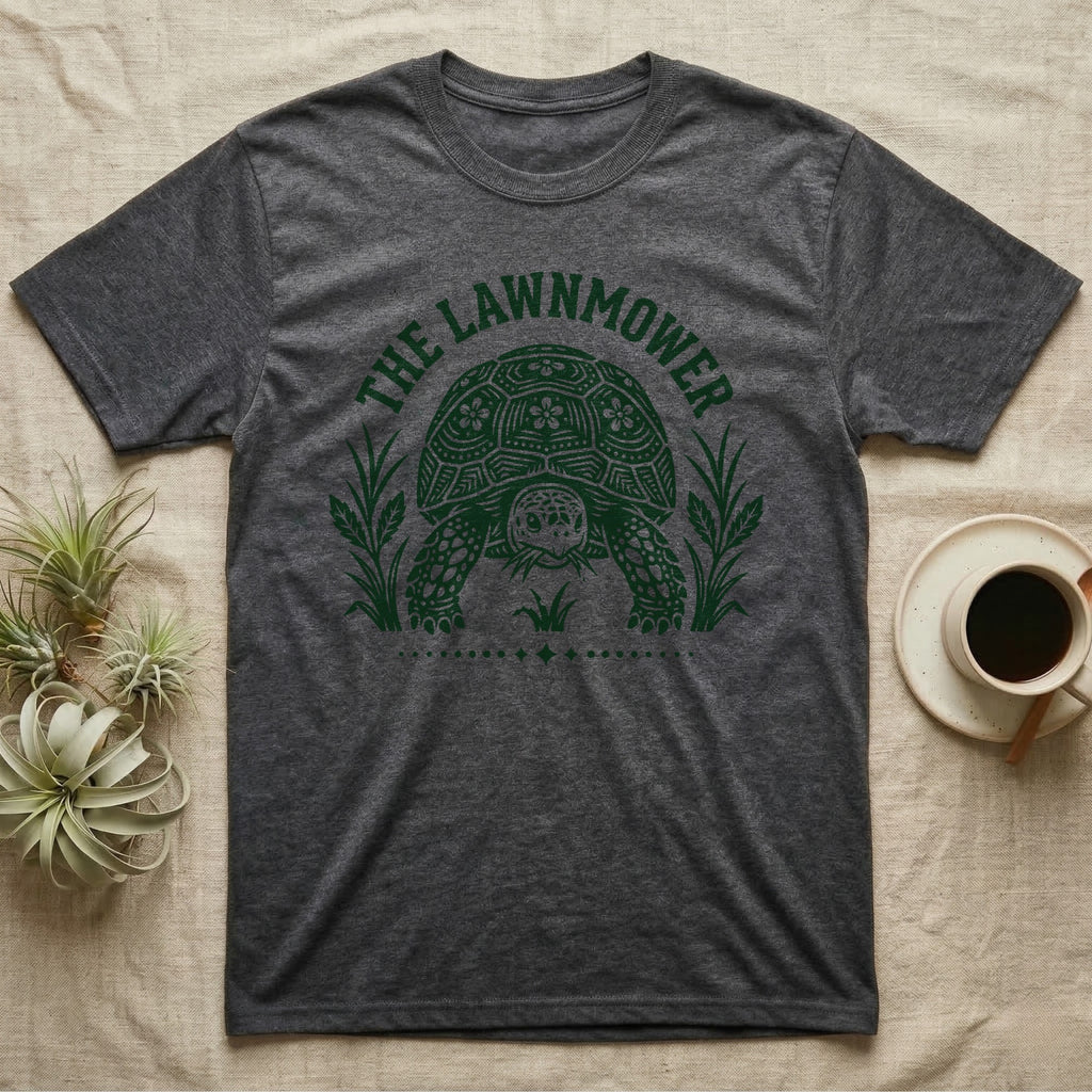 Sulcata Tortoise Under Lawn T-Shirt in Dark Heather — Engraved sulcata tortoise in white line, head down and legs braced mid-dig, under retro script reading UNDER THE LAWN.