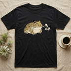 Pacman Frog Blossom T-Shirt in Black — Watercolor illustration of an olive-tan Pacman frog holding a water-lily blossom sprig, on a dark grey t-shirt.