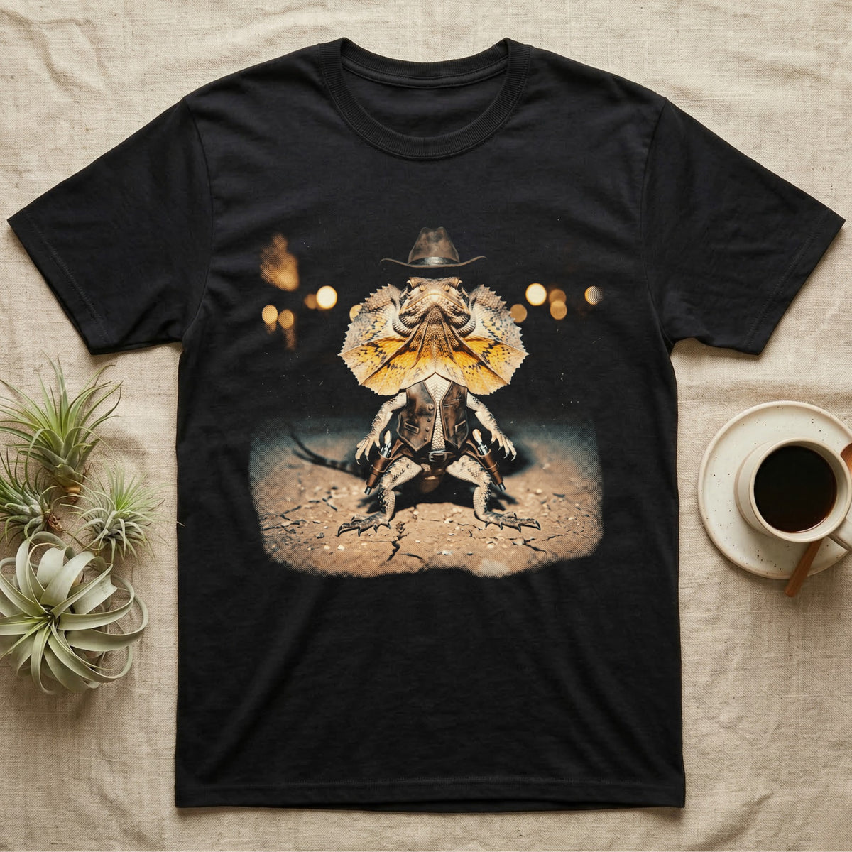 Frilled Lizard Outlaw T-Shirt in Black — Frilled lizard as a Wild West outlaw in a cowboy hat and twin holsters, frill flared, on cracked desert ground.
