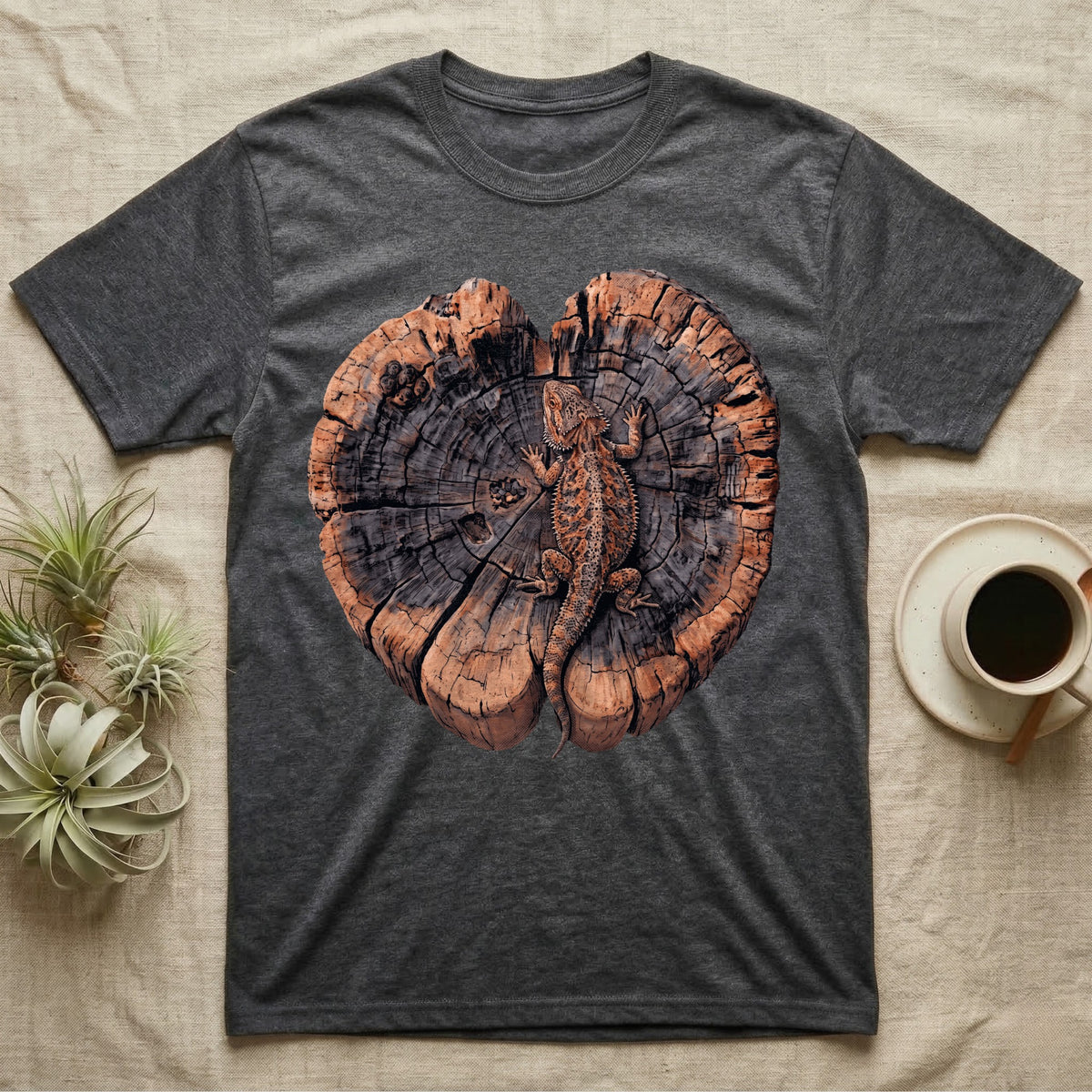 Bearded Dragon Basking Rings T-Shirt in Dark Heather — Top-down illustration of a bearded dragon splayed flat on a cross-section log slab of terracotta growth rings with bracket fungus, no on-shirt text.