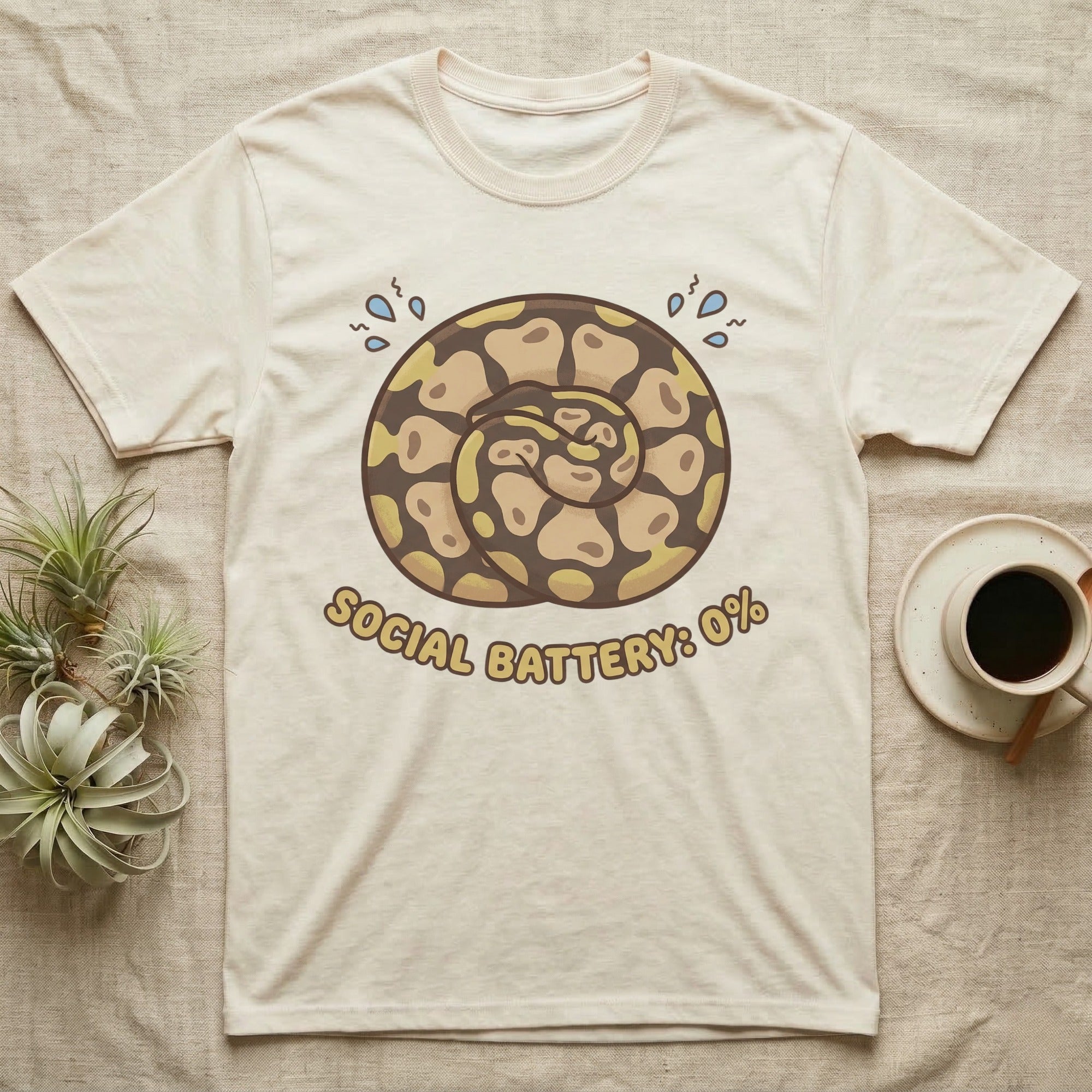 Cream t-shirt with coiled snake graphic and "SOCIAL BATTERY: 0%" text.