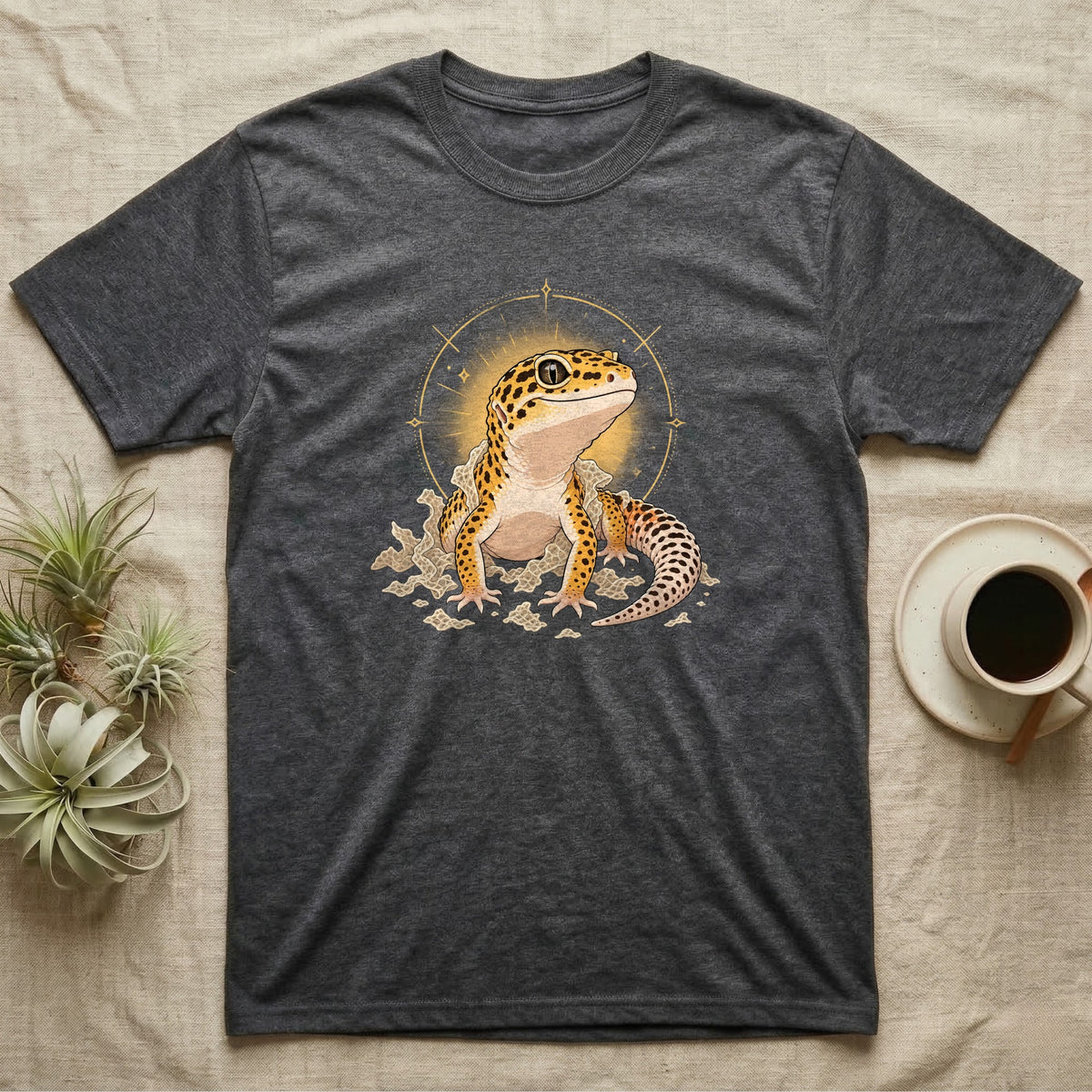 Leopard Gecko Shed T-Shirt in Dark Heather — Bold vector illustration of a leopard gecko emerging fresh from a shed, lit by a soft warm halo glow.