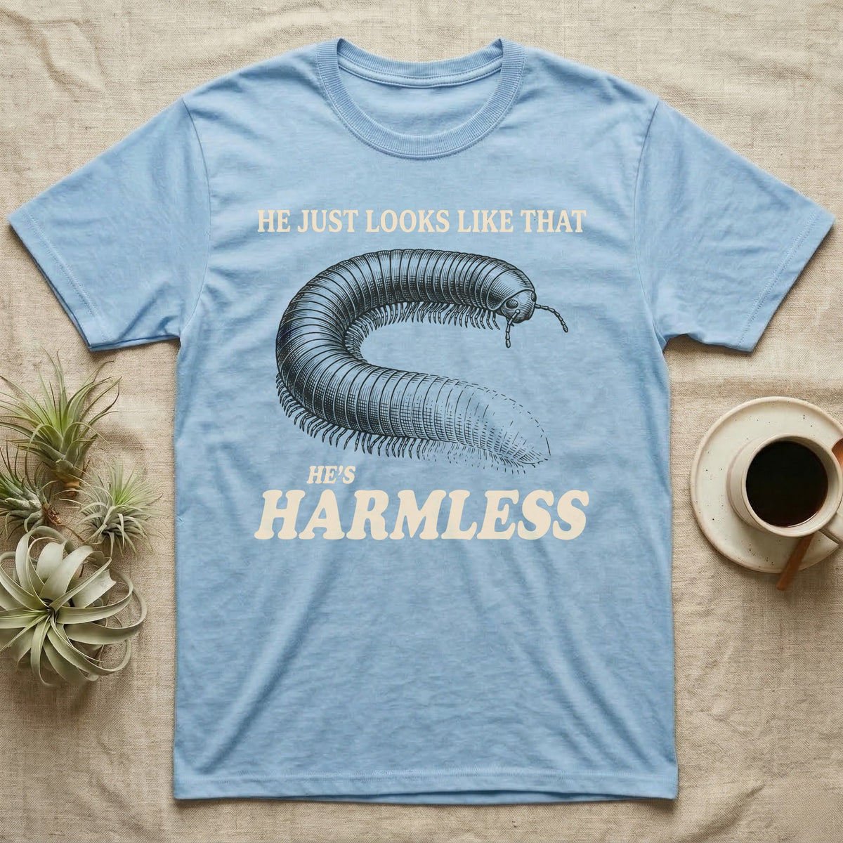 Millipede He's Harmless T-Shirt in Light Blue — Engraved giant African millipede between cream serif lines reading He Just Looks Like That and Harmless.
