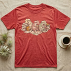 Gecko Book Club T-Shirt in Heather Red — Warm storybook illustration of three crested geckos in a cozy reading row, each beside a tiny stack of books.