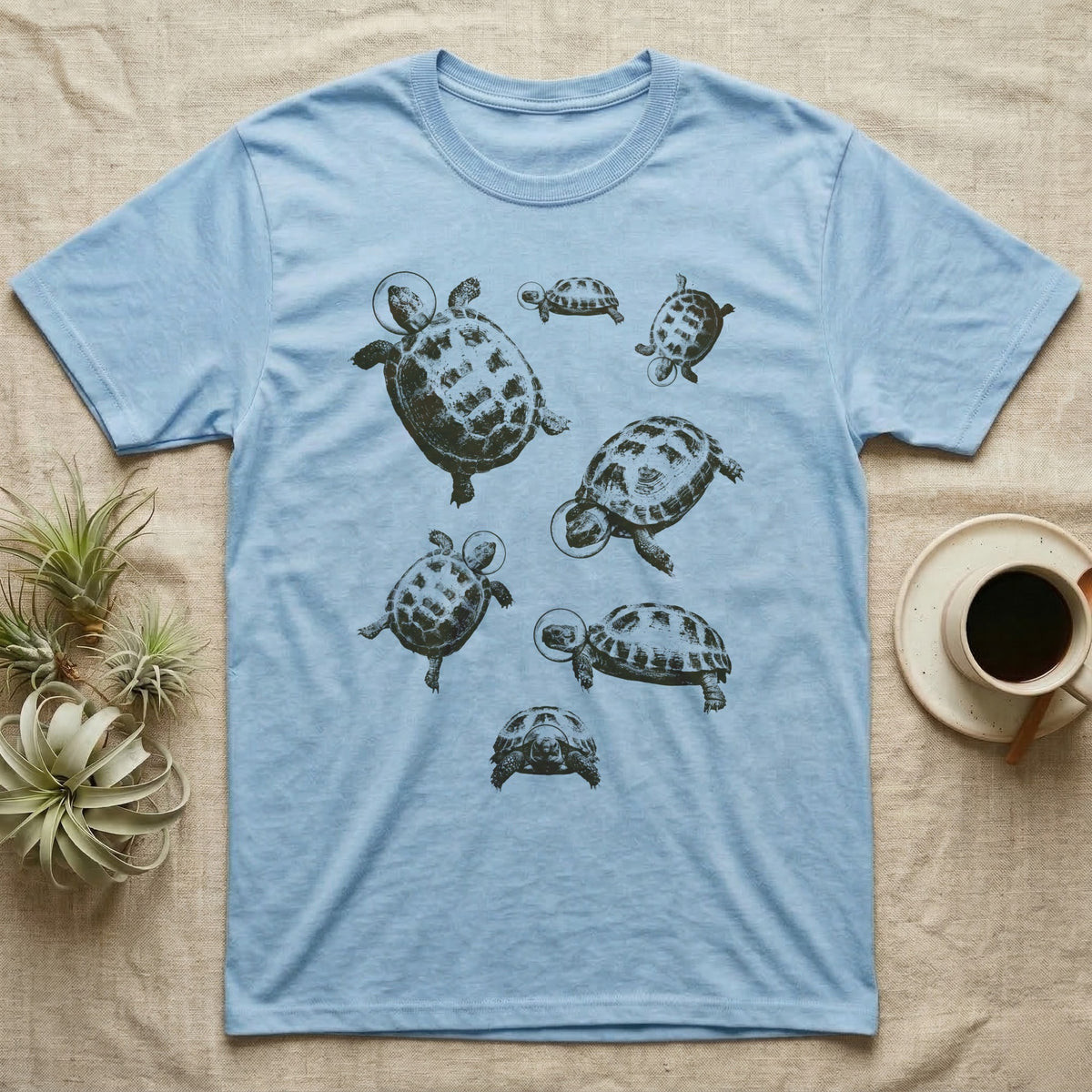 Russian Tortoise Space Helmets T-Shirt in Light Blue — One-ink screen print of seven Russian tortoises in rounded space helmets drifting at varied sizes.