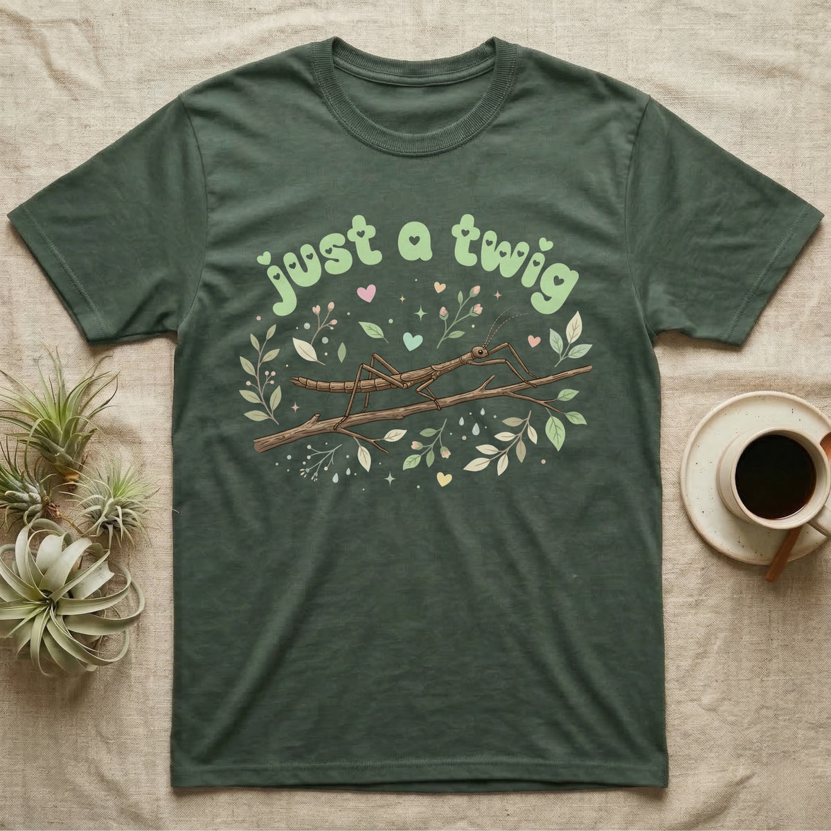 Stick Insect Softie T-Shirt in Military Green — Camouflaged stick insect on a branch under pastel bubble text "just a twig" with tiny hearts.