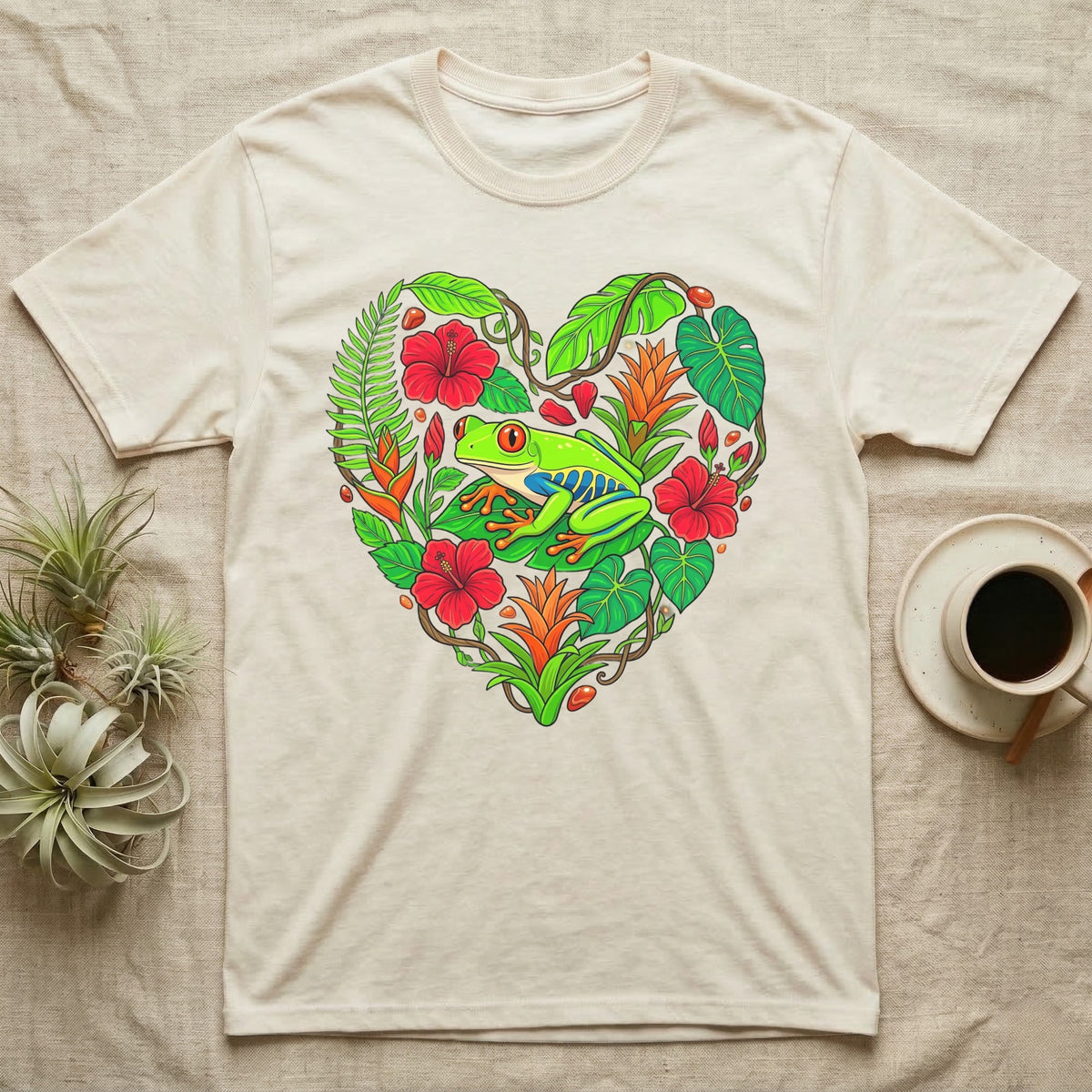 Cream t-shirt with a heart-shaped design of tropical leaves, flowers, and a frog.