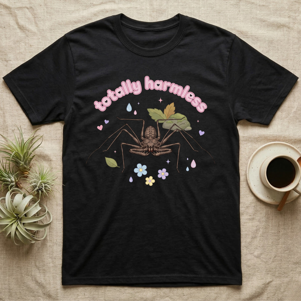 Tailless Whip Scorpion Baby T-Shirt in Black — Pastel tailless whip scorpion with long whip legs among leaves and blossoms, puffy pink wordmark "totally harmless" above.
