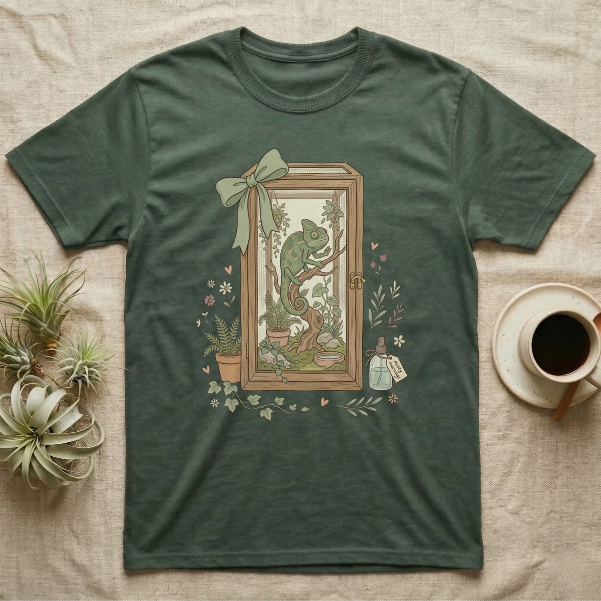 Green t-shirt with framed chameleon illustration, plants, and a potion bottle.