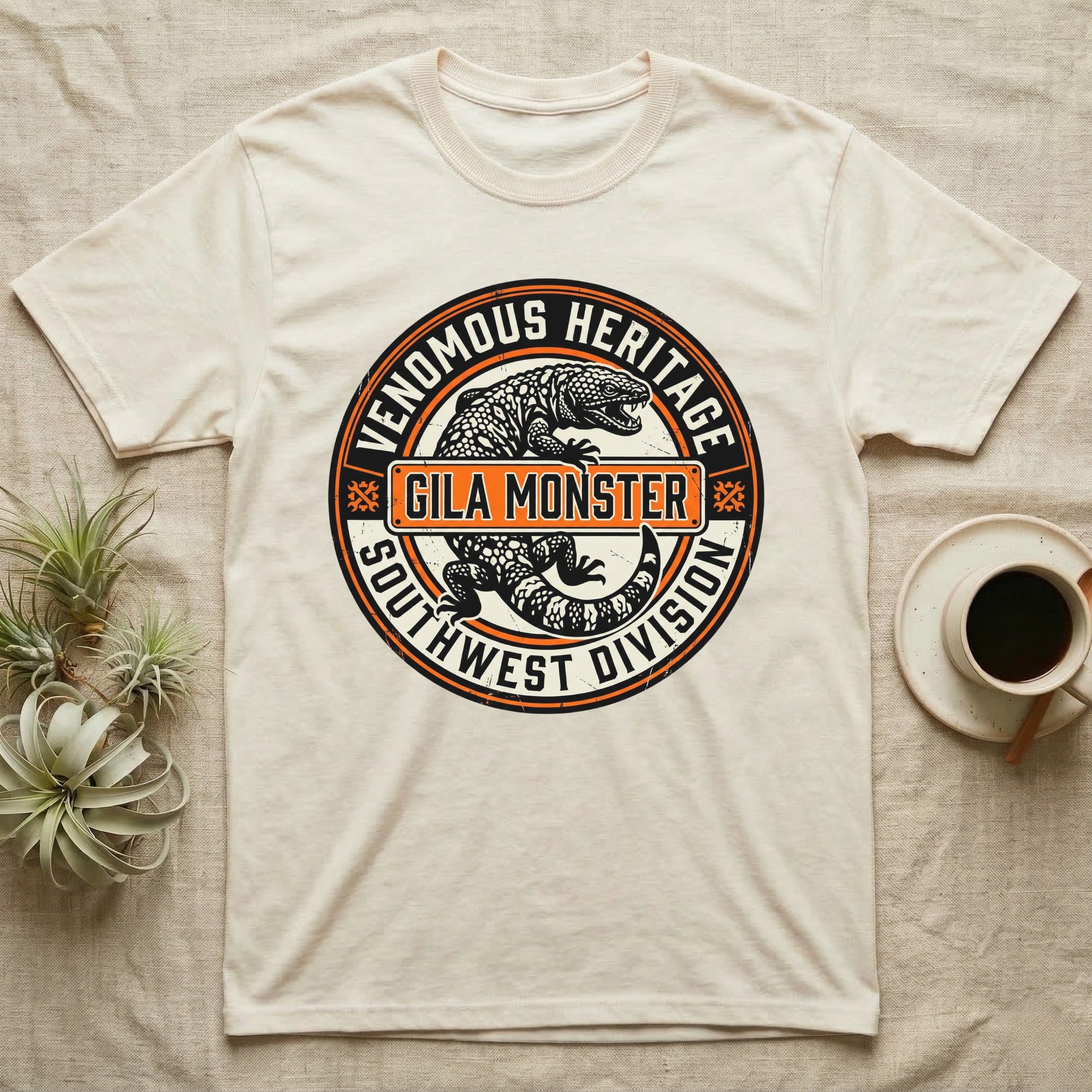Cream t-shirt with circular "Venomous Heritage Southwest Division Gila Monster" graphic.
