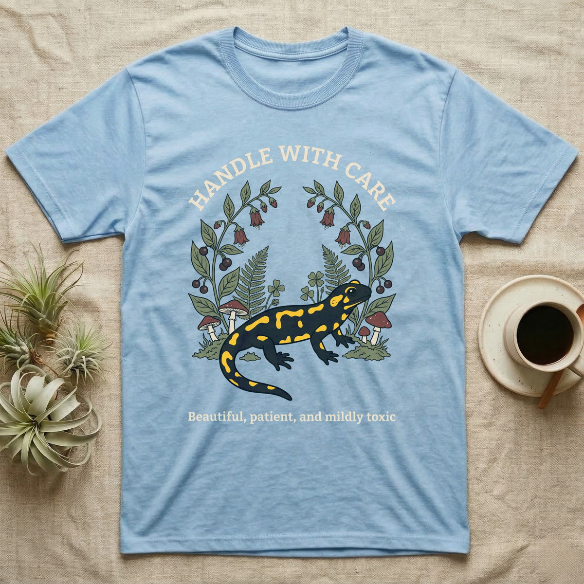 Fire Salamander Poison Plate T-Shirt in Light Blue — Naturalist apothecary-plate illustration of a fire salamander framed by a symmetric wreath of woodland botanicals.
