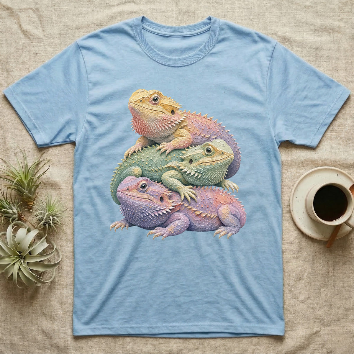 Three colorful bearded dragons stacked on a light blue t-shirt.