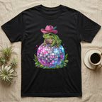 Frog wearing a pink cowboy hat sits on a disco ball surrounded by ferns.