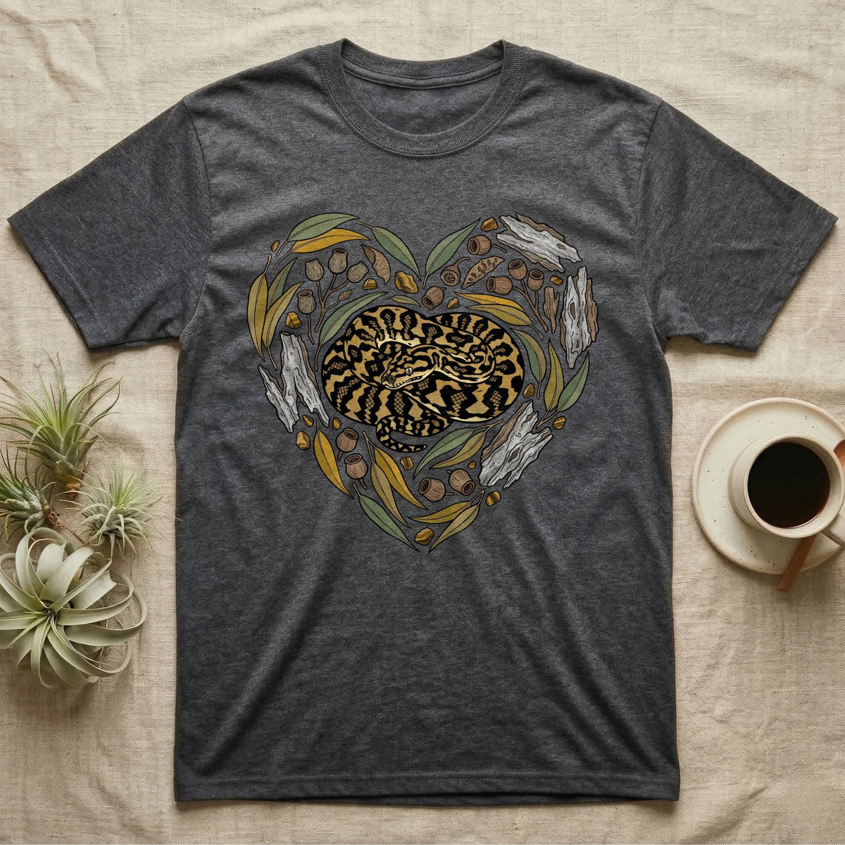 Dark grey t-shirt with a heart-shaped design of eucalyptus leaves, branches, and a snake.