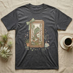 T-shirt graphic of a chameleon in a terrarium with plants and a green ribbon.