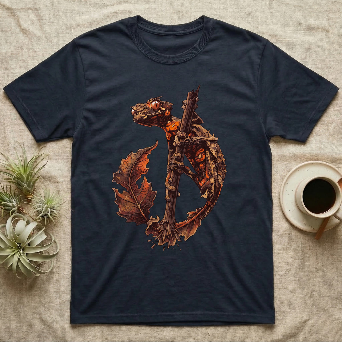 Vintage ink illustration of an eyelash leaf-tailed gecko clinging to a branch with its tail curled beside a serrated leaf, no on-shirt text. — shown on a Navy tee.