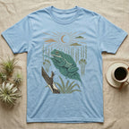 White's Tree Frog Home Range T-Shirt in Light Blue — Woodcut-style illustration of a White's tree frog resting on a broad wet leaf with reed stems and a crescent moon behind, no on-shirt text.