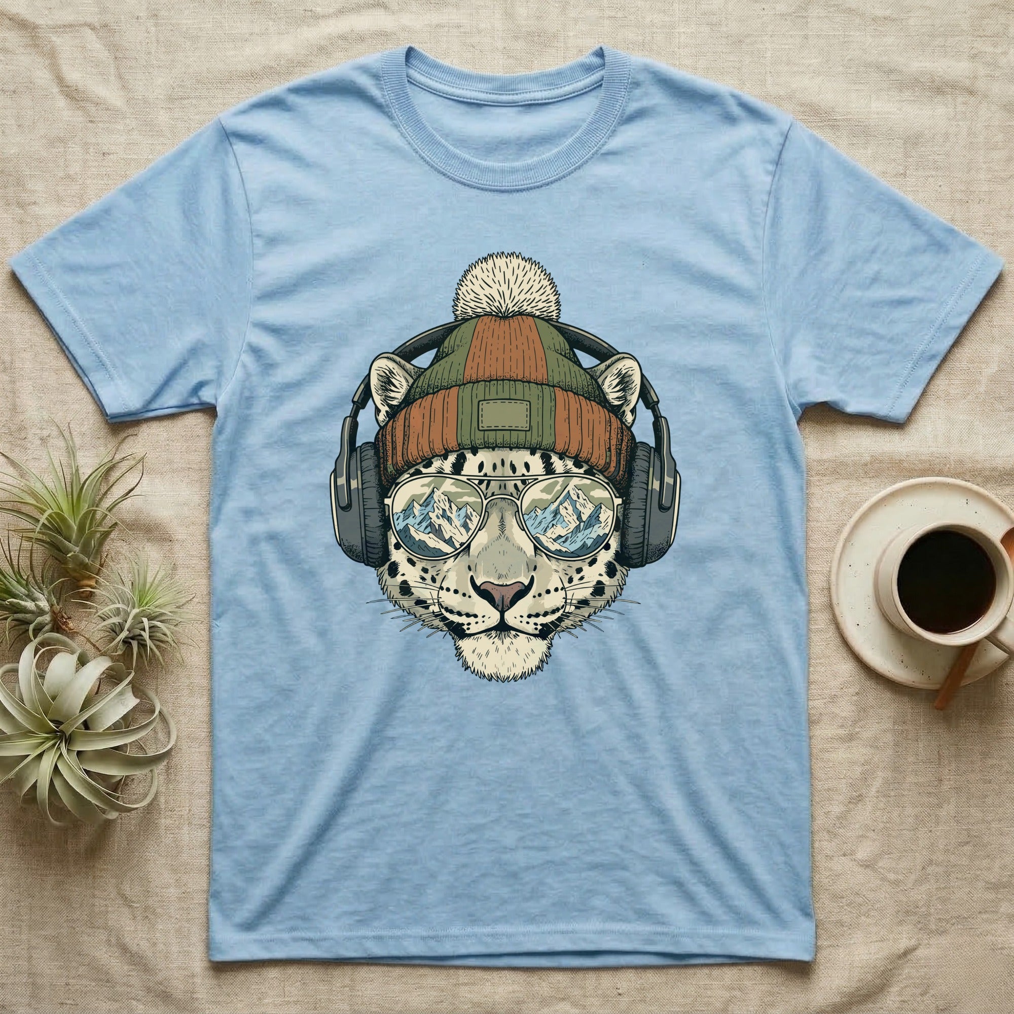 Blue t-shirt with a snow leopard illustration wearing headphones, beanie, and sunglasses.