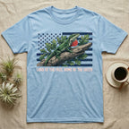Green Anole 1776 T-Shirt in Light Blue — Realistic green anole with a red dewlap on a branch over a distressed flag under text Land of the Free, Home of the Green.