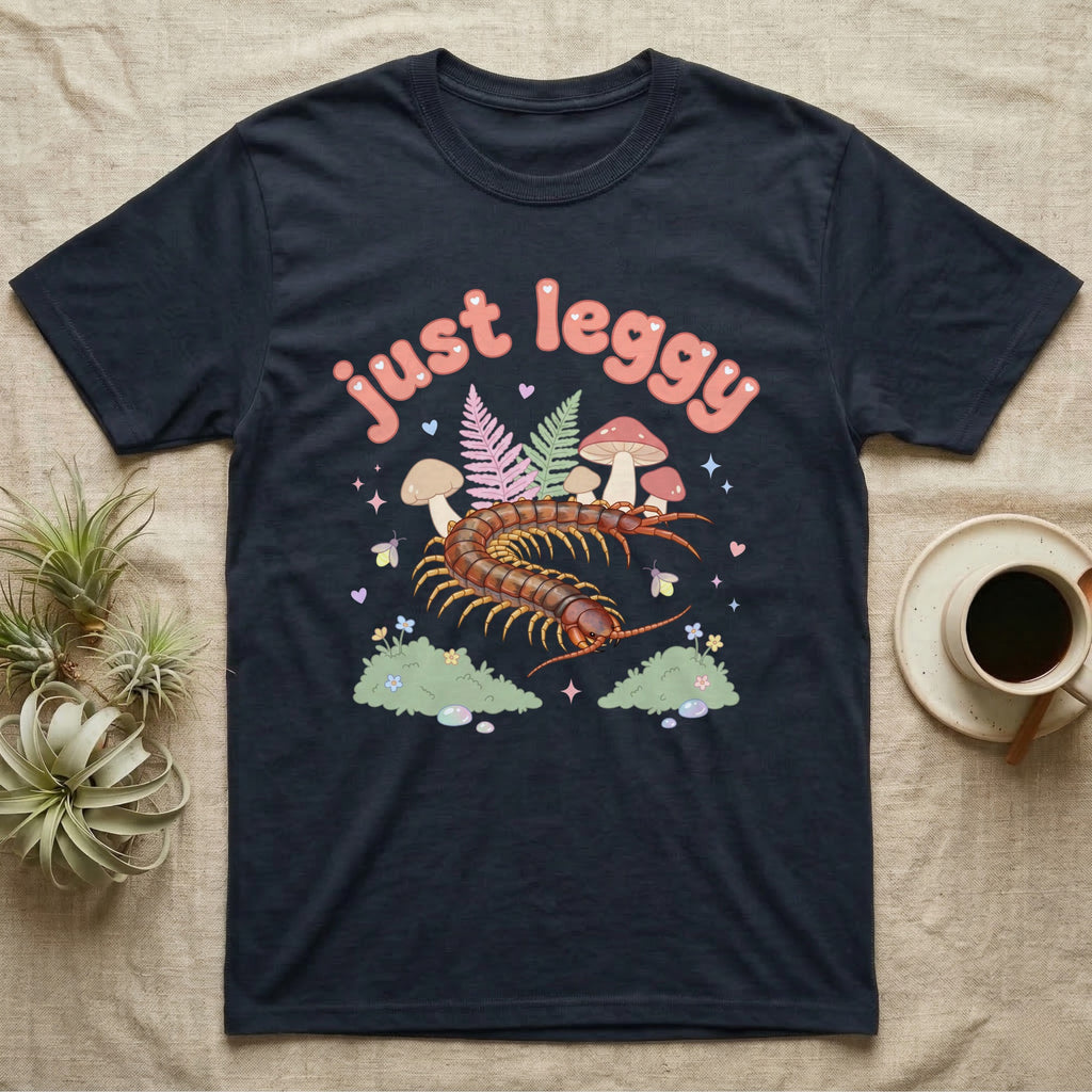 Vietnamese Centipede Baby T-Shirt in Navy — Many-legged Vietnamese centipede curving among pastel ferns and toadstools under puffy coral text "just leggy".