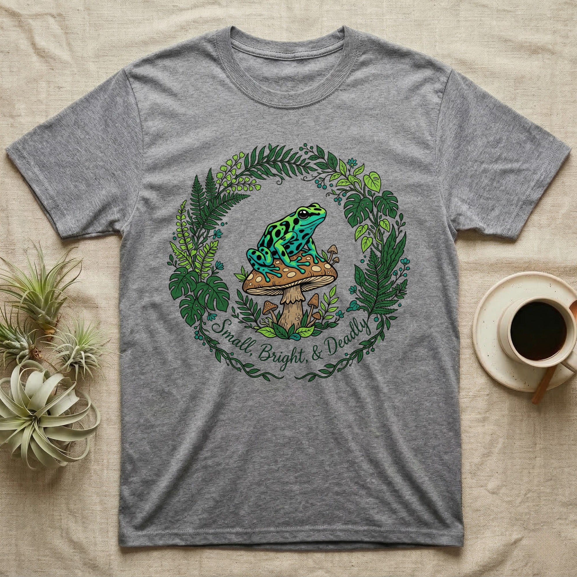Gray t-shirt with frog on mushroom and floral wreath graphic.