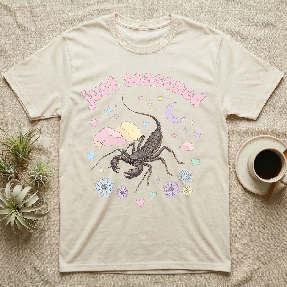 Giant Vinegaroon Baby T-Shirt in Natural — Pastel giant vinegaroon with pincers and whip tail among rocks and a crescent moon, puffy pink wordmark "just seasoned" above.